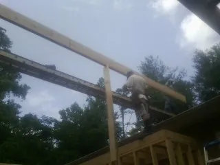 Carpenter setting a ridge beam over a new addition frame — Ice Dam Removal by Roofing Brothers in Edmeston