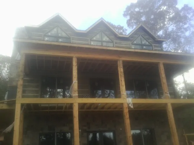 Dormers and porch framing on a large log home under construction — Roof Coating work by our crew in Edmeston