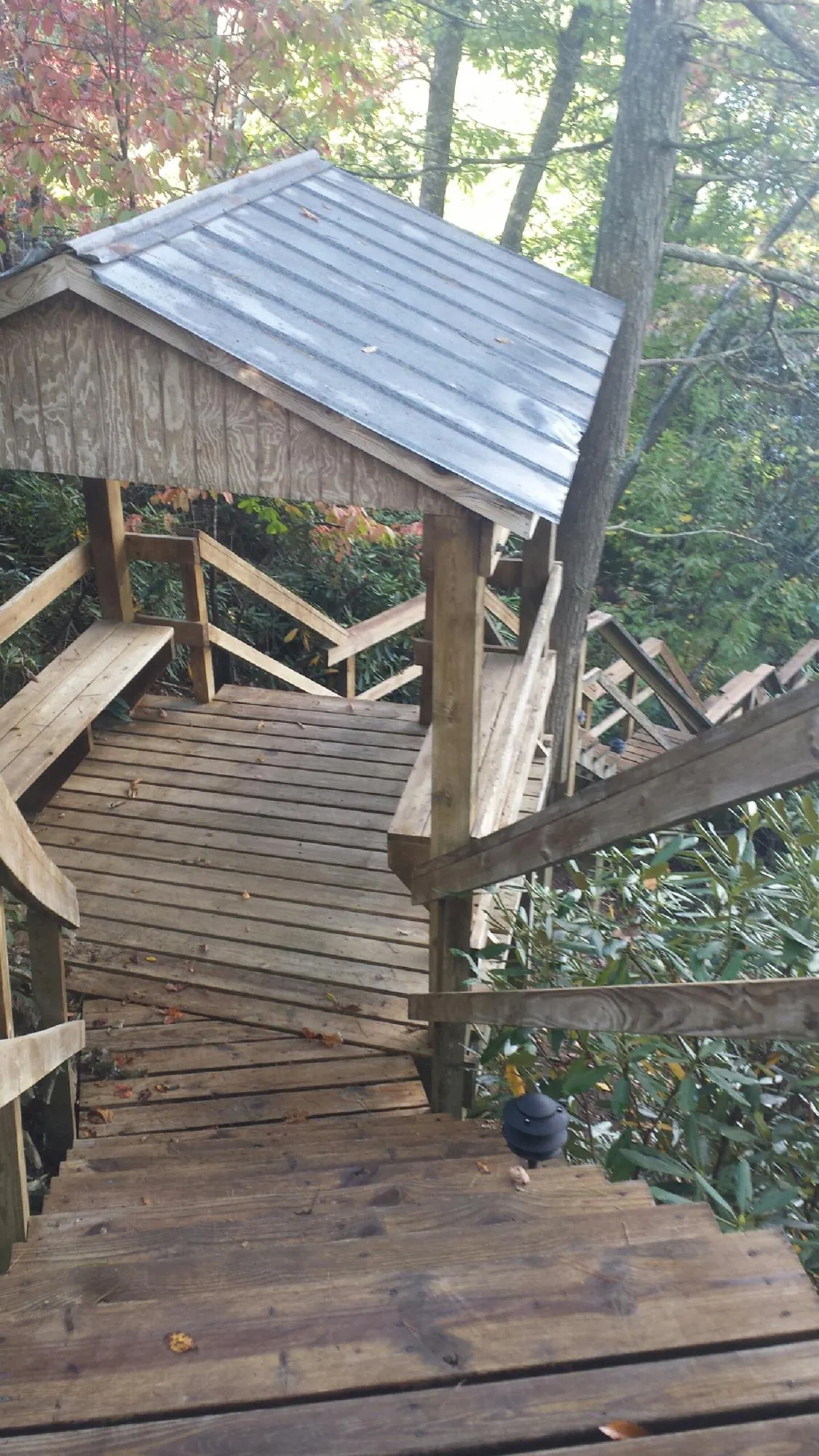 Metal roofed shelter over wooden steps on a wooded walkway — Skylight Repair & Installation work by our crew in Edmeston