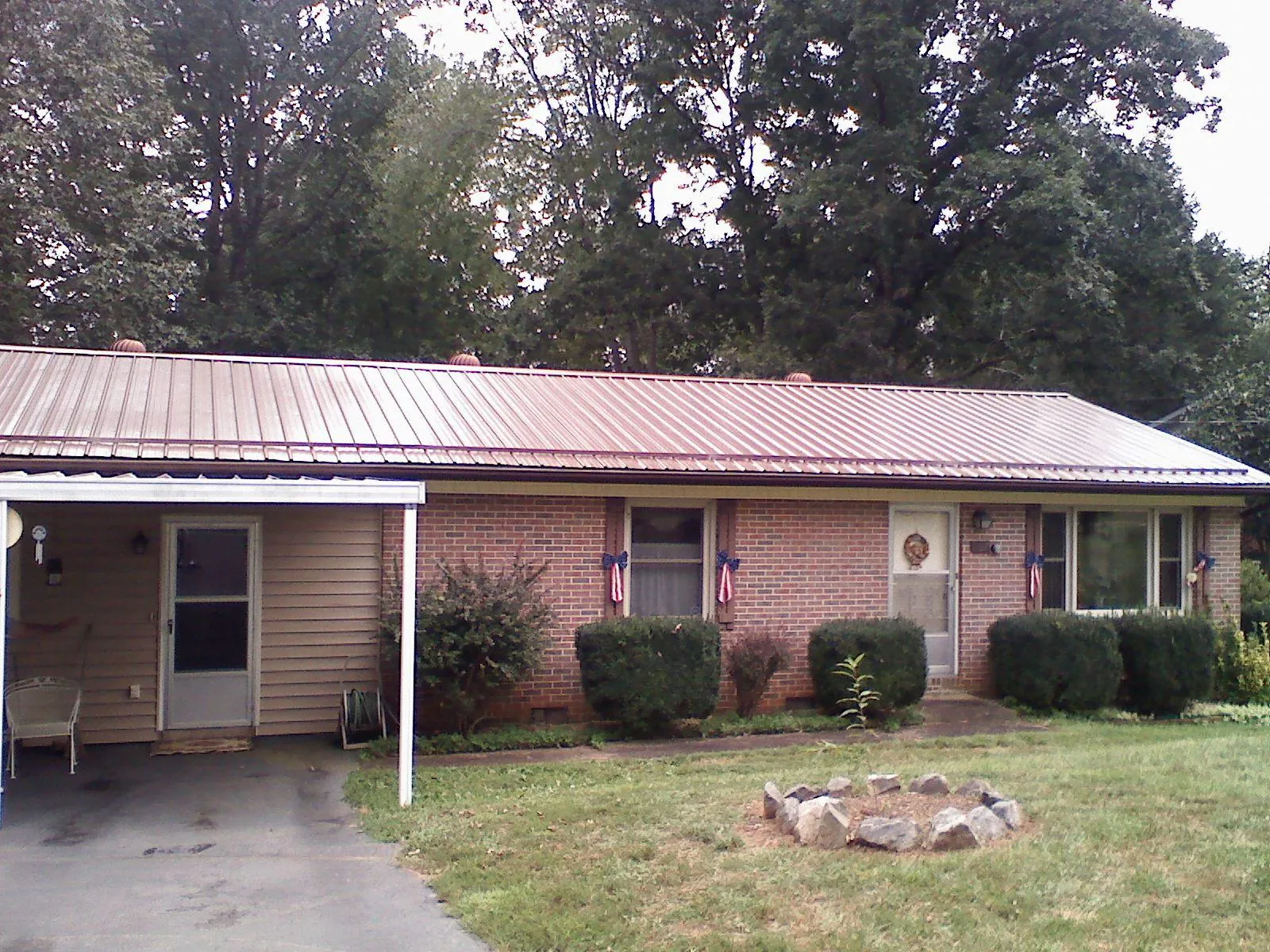 Bronze metal roof and carport on a brick ranch home — Roof Repair work by our crew in Edmeston