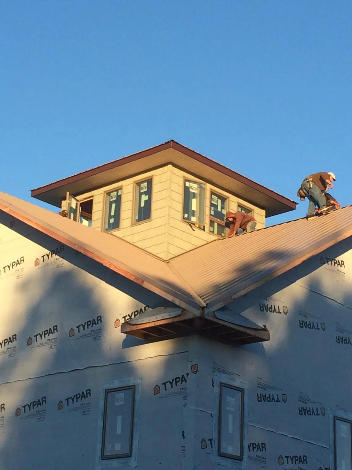 Roofers working around a rooftop cupola on a new metal roof at sunset — Roof Waterproofing in Edmeston by Roofing Brothers